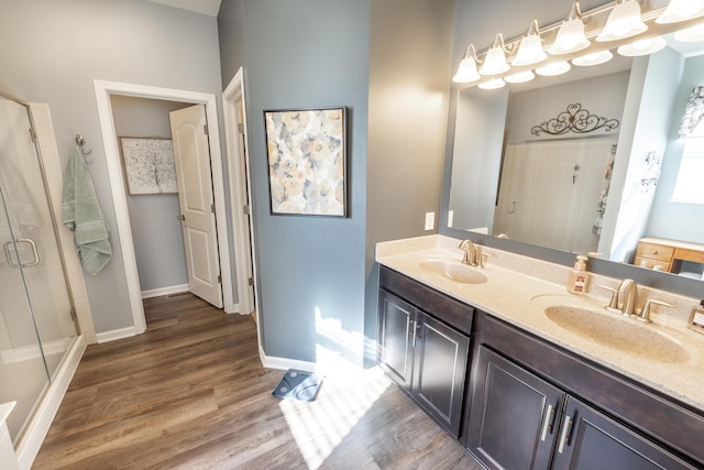 bathroom with baseboards, wood finished floors, a stall shower, and a sink