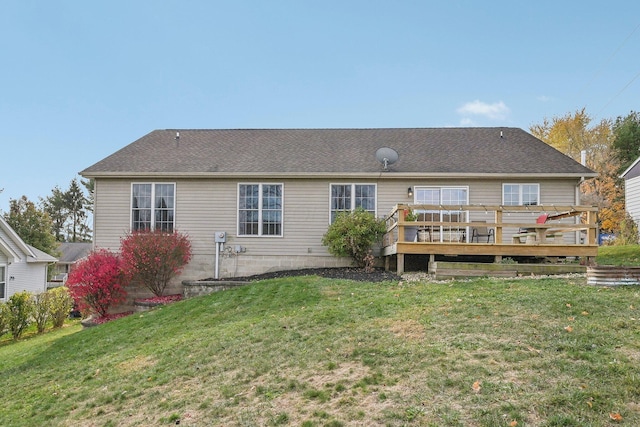 rear view of house with a shingled roof, a lawn, and a wooden deck