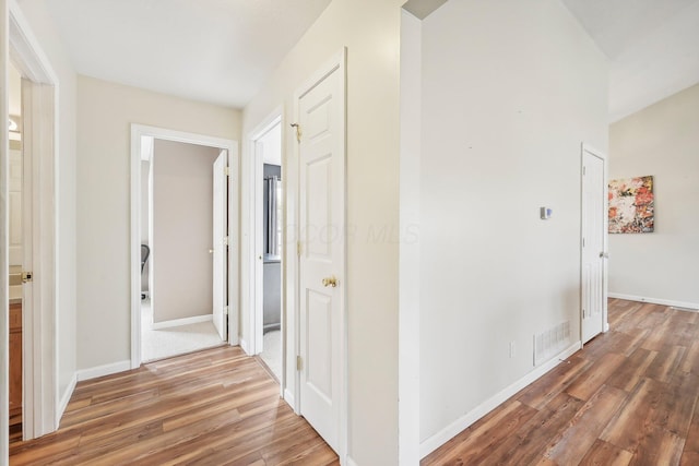 corridor with visible vents, light wood-style flooring, and baseboards