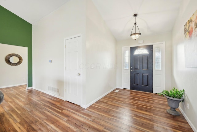 entryway with lofted ceiling, wood finished floors, visible vents, and baseboards