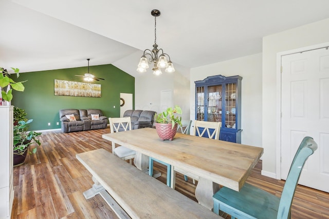 dining space with a notable chandelier, baseboards, vaulted ceiling, and wood finished floors