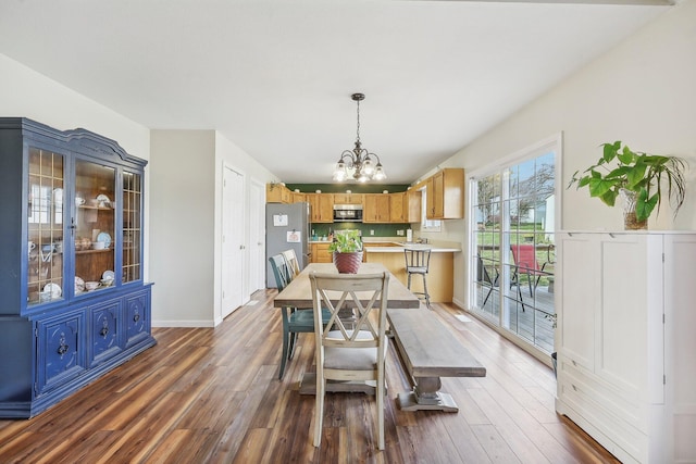 dining area featuring baseboards, wood finished floors, and an inviting chandelier