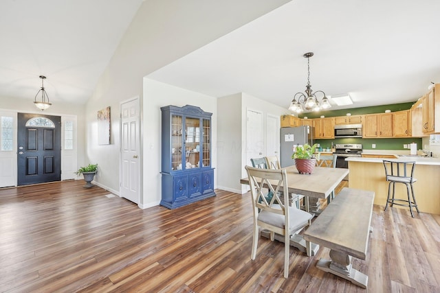 dining room with lofted ceiling, baseboards, a chandelier, and wood finished floors