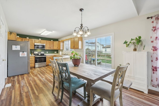 dining area with light wood finished floors and an inviting chandelier