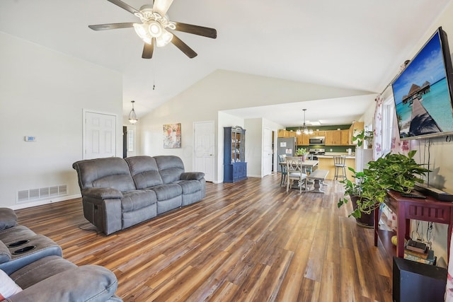 living room with ceiling fan with notable chandelier, high vaulted ceiling, wood finished floors, and visible vents