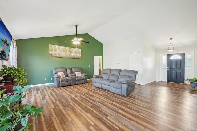 living room featuring a ceiling fan, baseboards, vaulted ceiling, and wood finished floors