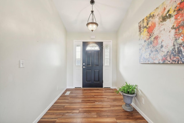 entryway featuring lofted ceiling, baseboards, and wood finished floors