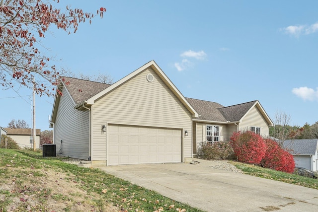 single story home featuring a garage, concrete driveway, central AC unit, and roof with shingles