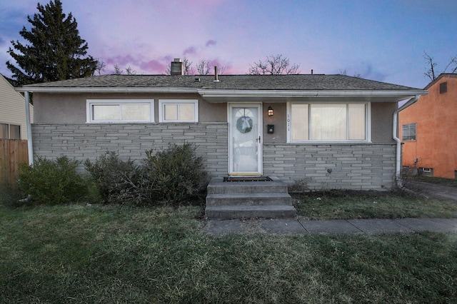 view of front facade with stone siding, a yard, a chimney, and stucco siding