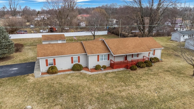 ranch-style house with a front lawn, a shingled roof, fence, and a wooden deck