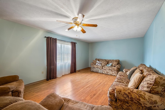 living room featuring a ceiling fan, a textured ceiling, and light wood finished floors