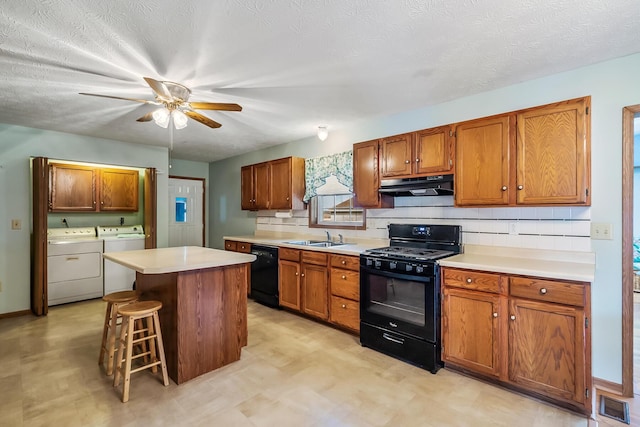 kitchen with visible vents, a kitchen island, independent washer and dryer, under cabinet range hood, and black appliances