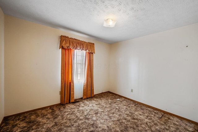 carpeted spare room featuring a textured ceiling and baseboards