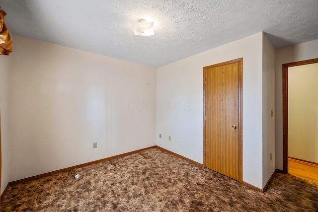 unfurnished bedroom with a textured ceiling, a closet, baseboards, and carpet flooring