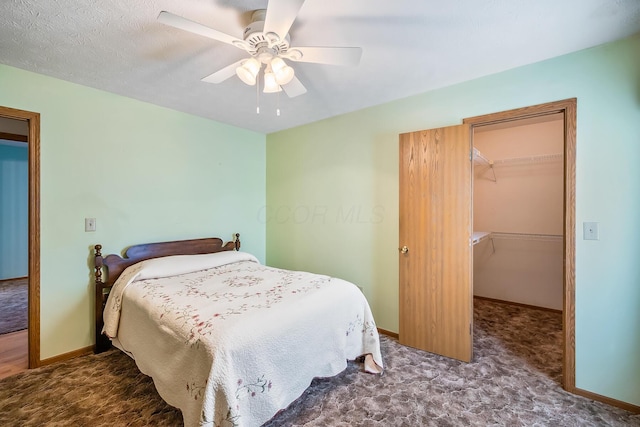 carpeted bedroom with ceiling fan, a spacious closet, baseboards, and a closet