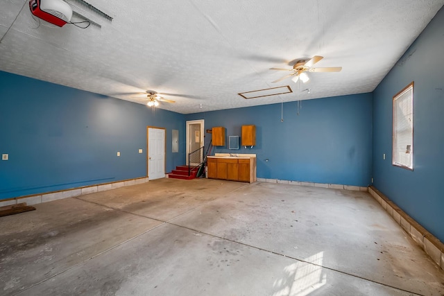 interior space featuring attic access, unfinished concrete floors, baseboards, and a textured ceiling