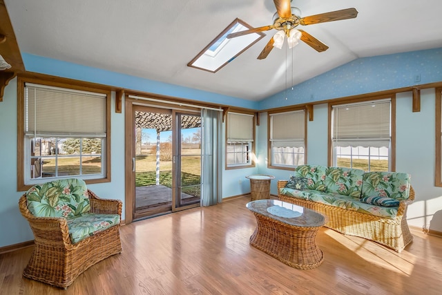 sunroom featuring lofted ceiling with skylight, plenty of natural light, and a ceiling fan