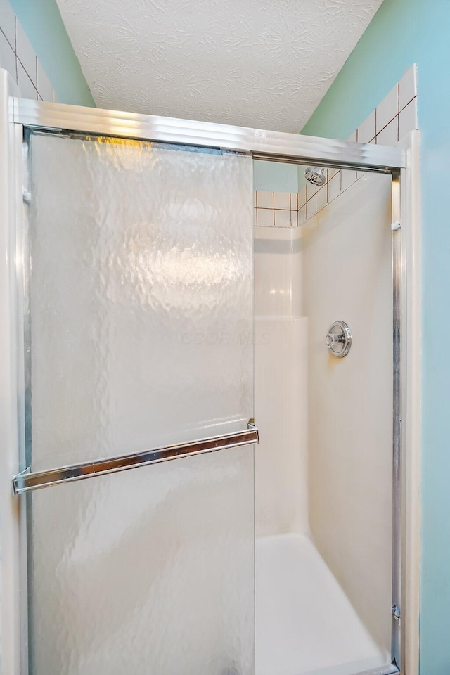 full bath with a shower stall and a textured ceiling