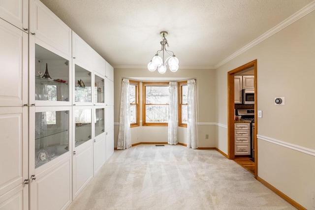 unfurnished dining area featuring a textured ceiling, a chandelier, crown molding, baseboards, and light colored carpet