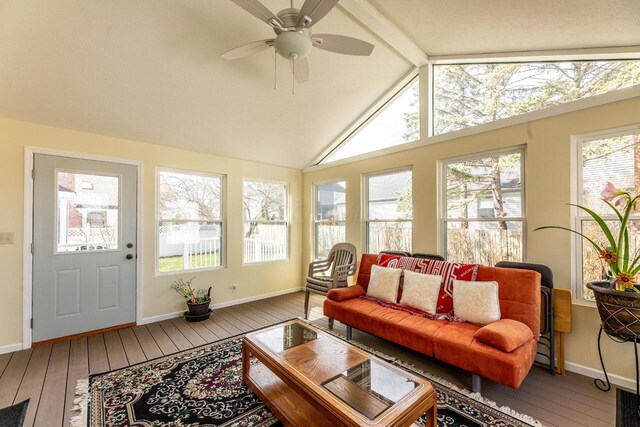 sunroom / solarium featuring baseboards, vaulted ceiling with beams, a wooden deck, and wood-type flooring