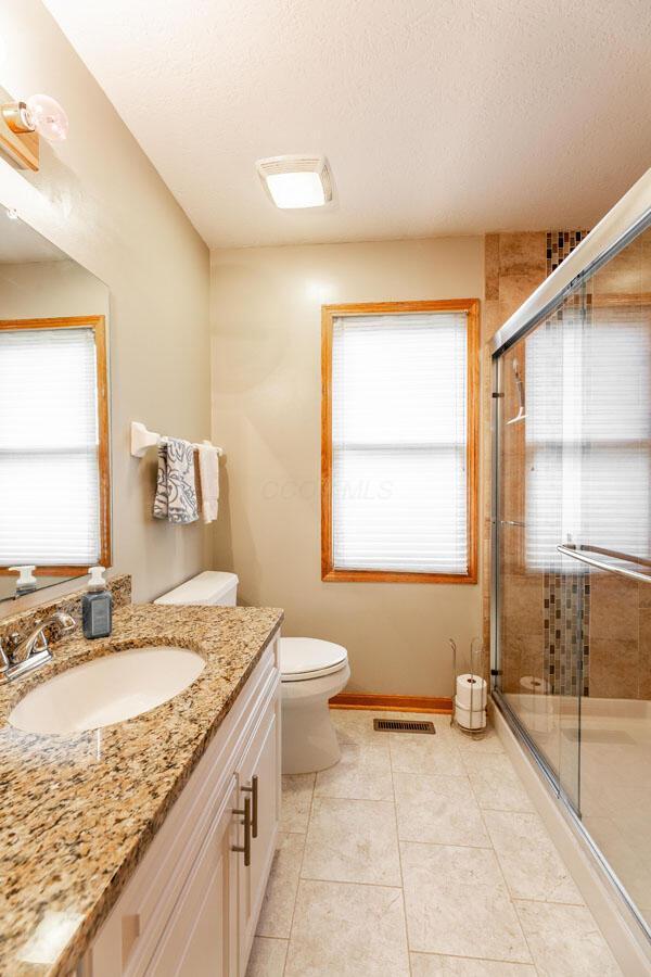 full bath with a shower stall, a wealth of natural light, visible vents, and toilet