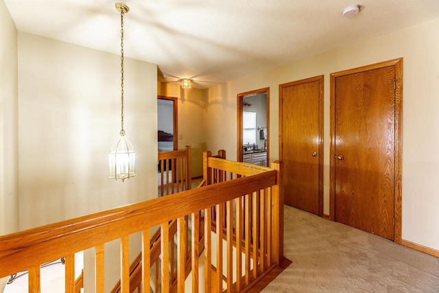 corridor with an upstairs landing and light carpet