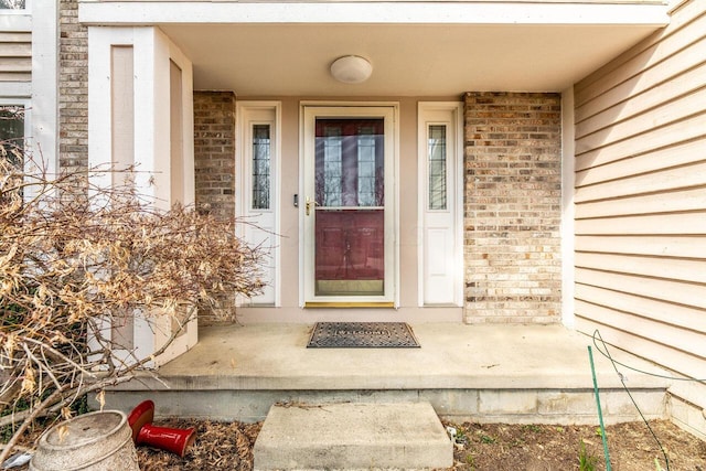 view of exterior entry featuring brick siding
