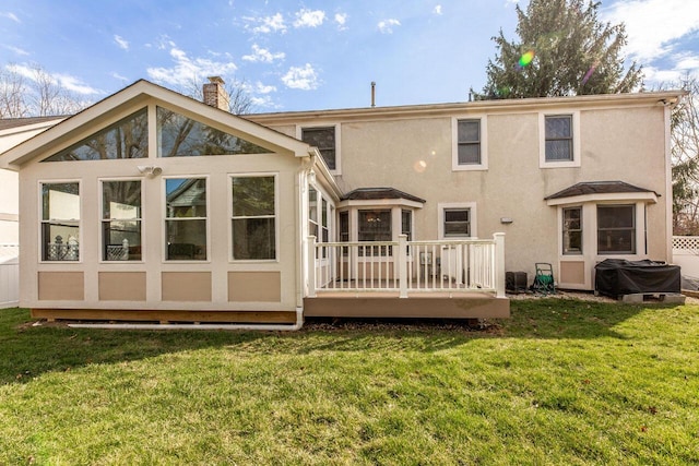rear view of property with a wooden deck, stucco siding, a yard, and a chimney