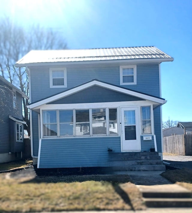 view of front of house featuring fence, a sunroom, and metal roof