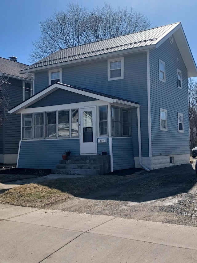 view of front of house with entry steps, metal roof, a standing seam roof, and a sunroom