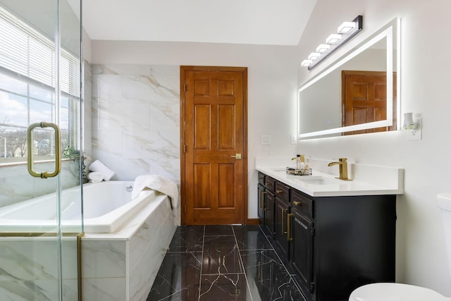 bathroom with toilet, marble finish floor, a bath, and vanity