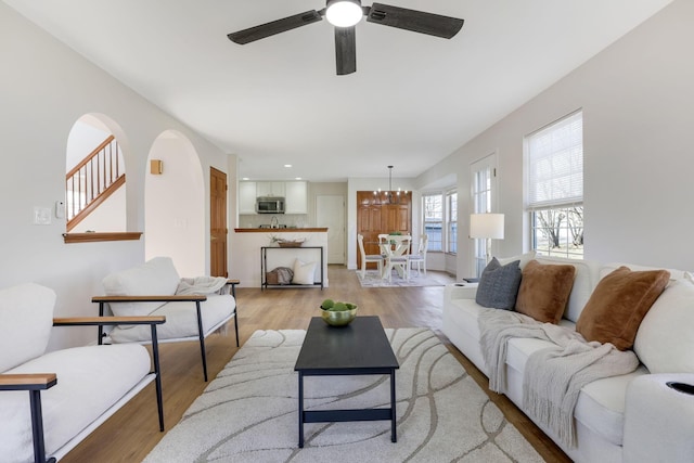 living area featuring ceiling fan with notable chandelier and light wood-style floors