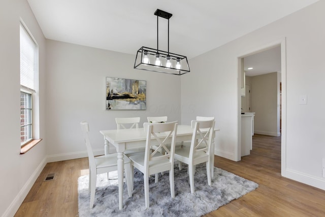 dining area with light wood finished floors, visible vents, and baseboards