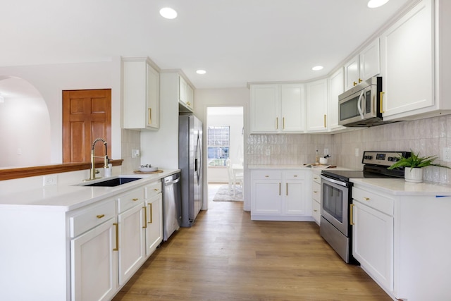 kitchen with light wood-style flooring, white cabinets, appliances with stainless steel finishes, and a sink