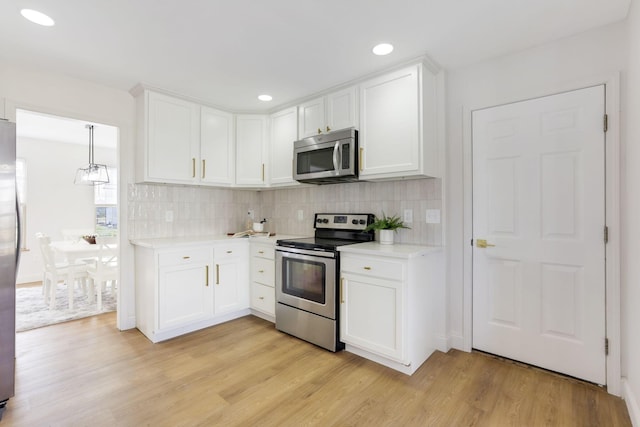 kitchen featuring decorative backsplash, light countertops, light wood-type flooring, and appliances with stainless steel finishes