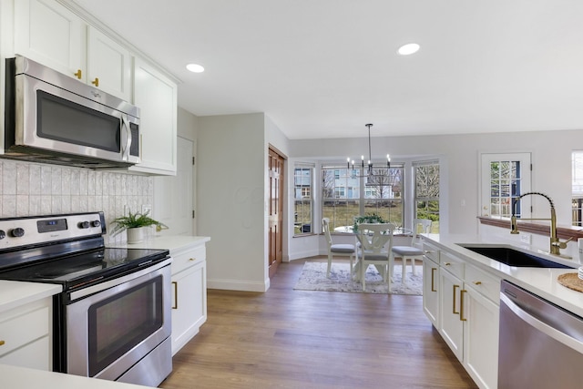 kitchen featuring a sink, backsplash, appliances with stainless steel finishes, and light countertops