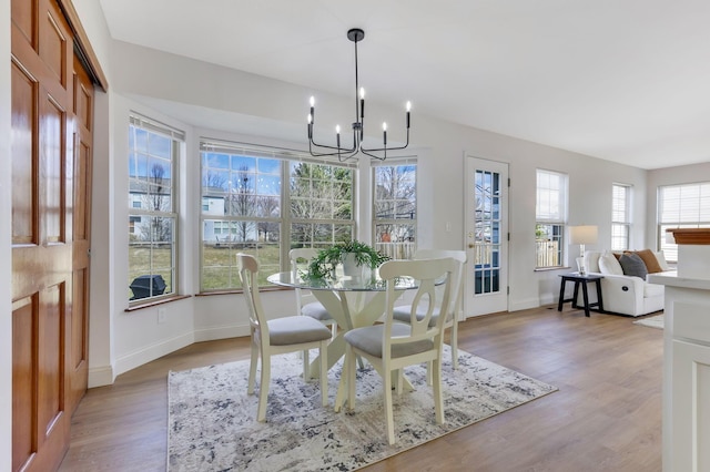 dining space with an inviting chandelier, light wood-style floors, and baseboards