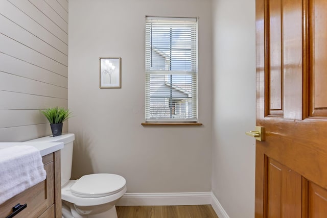 bathroom with toilet, wood finished floors, and baseboards