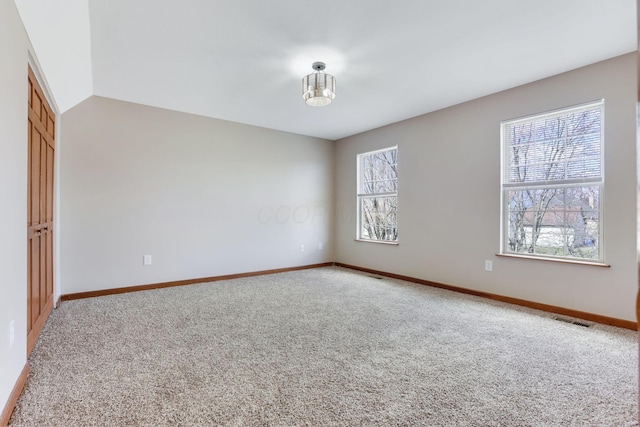 spare room with visible vents, light colored carpet, and baseboards