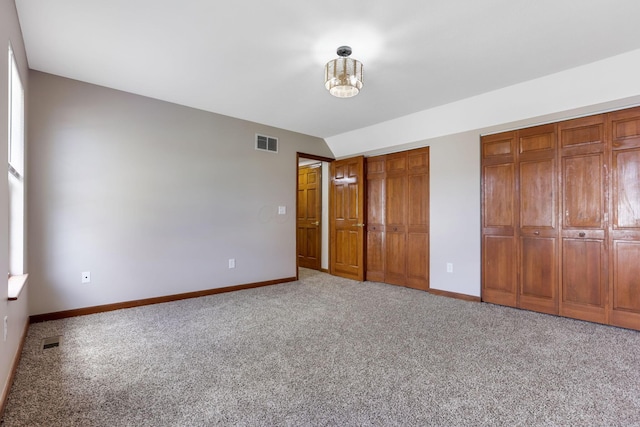 unfurnished bedroom with visible vents, carpet flooring, baseboards, and multiple closets