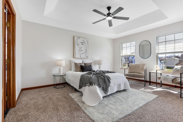 bedroom featuring baseboards, a raised ceiling, carpet, and ceiling fan