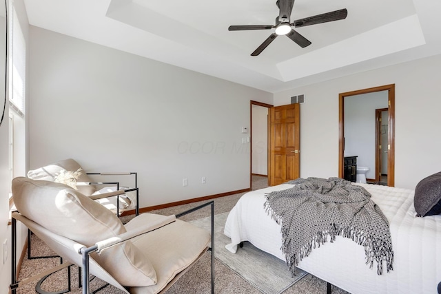 carpeted bedroom featuring visible vents, ceiling fan, baseboards, and a tray ceiling