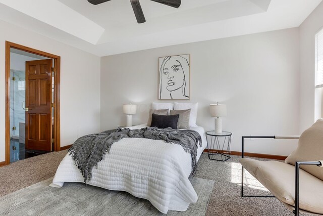 carpeted bedroom with a tray ceiling, a ceiling fan, and baseboards