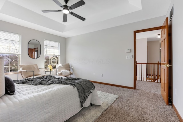 bedroom with visible vents, a ceiling fan, a tray ceiling, carpet floors, and baseboards