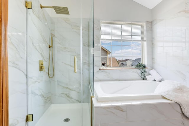 bathroom featuring lofted ceiling, a garden tub, and a marble finish shower