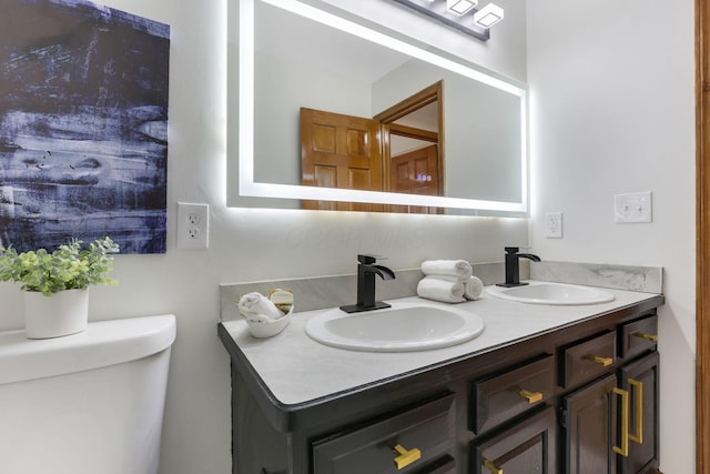 bathroom featuring double vanity, toilet, and a sink