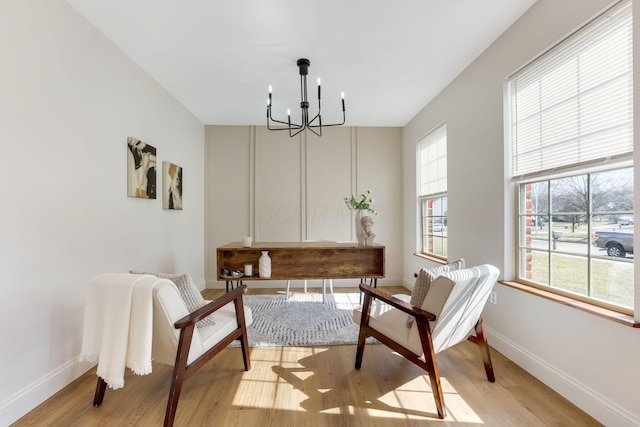 sitting room with baseboards, light wood-type flooring, and a chandelier