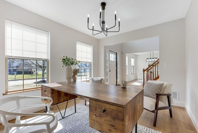 office space with a chandelier, visible vents, plenty of natural light, and light wood-style floors