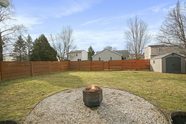 view of yard featuring a fenced backyard, a fire pit, a storage unit, and an outdoor structure