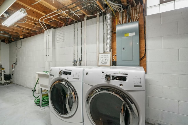 washroom featuring electric panel, washing machine and dryer, and laundry area